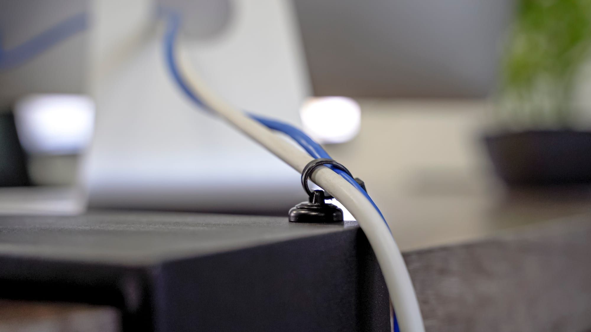 Cables held by a magnetic mount on the edge of a metal desk