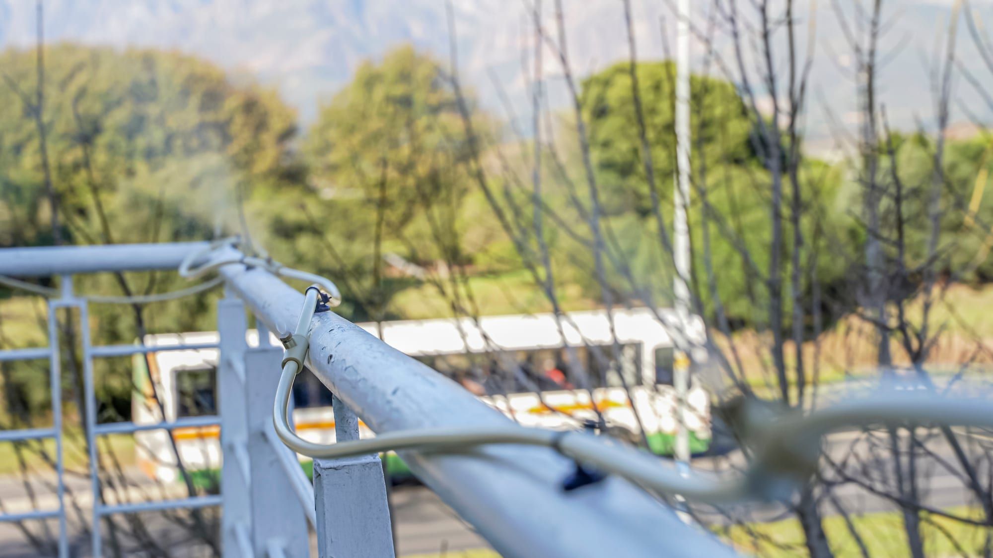 Irrigation hose held by magnetic mounts along a steel balcony railing